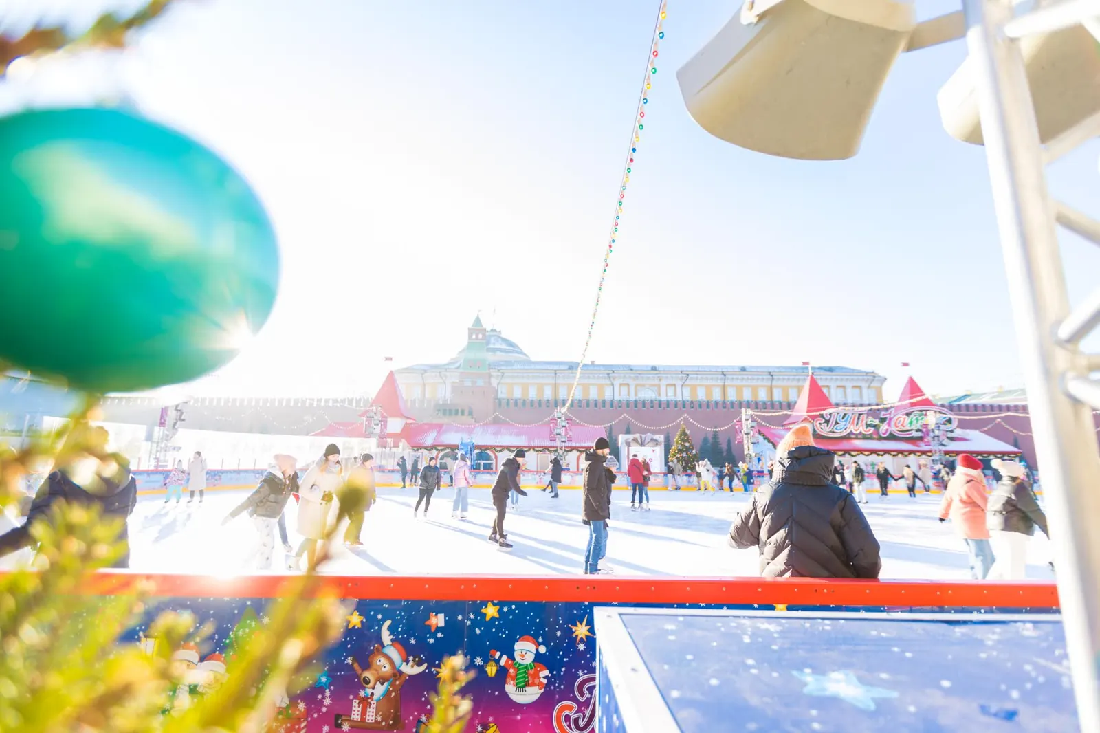 Sân băng GUM ban ngày, người trượt băng, phía sau là tường Kremlin và mái vòm Toà nhà Thượng viện